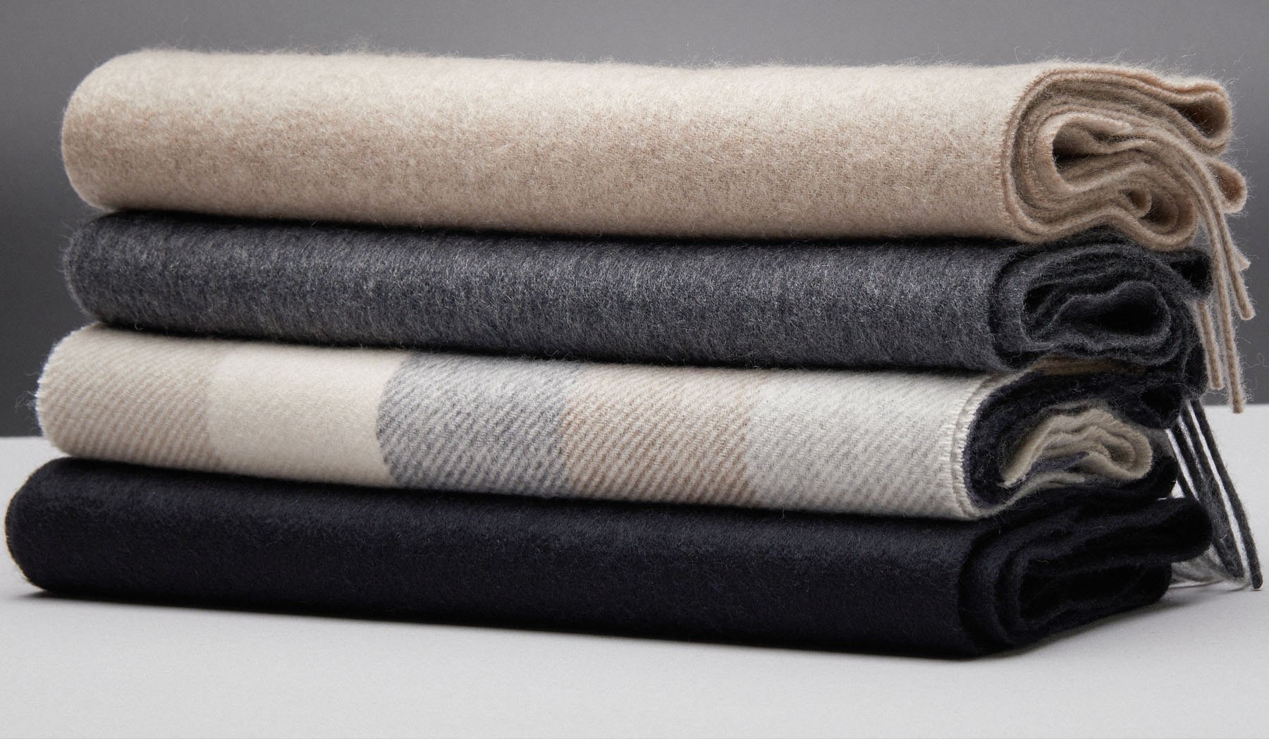 Folded wool scarves in oatmeal, charcoal, cream check and black